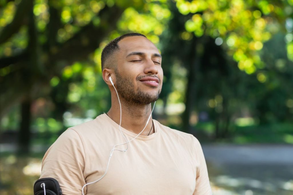 Person under trees with ear buds in and eyes closed